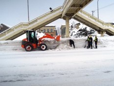 歩道橋付近でタイヤショベルが除雪する様子